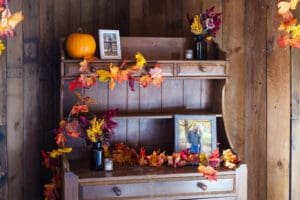 Wooden shelf decorated with autumn leaves, pumpkin.